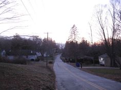 an empty street with houses and trees in the background