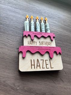 a wooden sign with candles on it that says happy birthday hazel in front of them