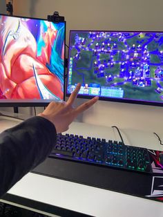 a person reaching out their hand in front of two computer monitors with the same image on them