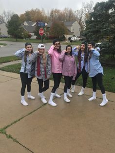 four girls are standing on the sidewalk in front of a stop sign