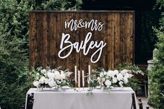 a table with flowers and candles in front of a wooden sign that says the smiths