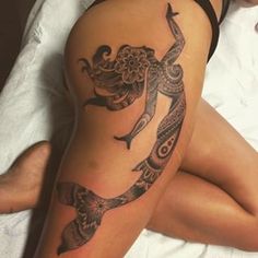 a woman laying on top of a bed with a tattoo on her arm and leg