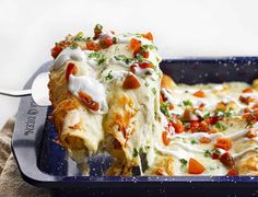 a casserole dish with tomatoes and cheese being lifted from the casserole