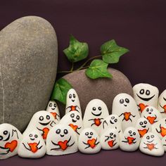 a group of rocks with faces painted on them next to a rock and ivy plant