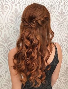 a woman with long red hair is standing in front of a wall