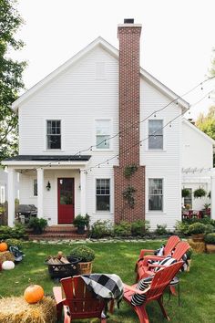 a white house with pumpkins and hay in front