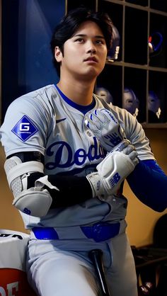 a baseball player sitting in the dugout with his gloved hands on his knees