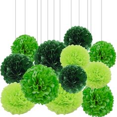 green tissue pom - poms hanging from strings in front of a white background