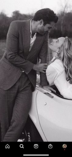 a man and woman leaning on the hood of a car