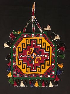 an embroidered piece with tassels hanging from it's sides on a black background