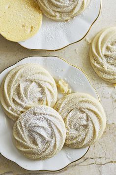 three white plates topped with cookies covered in powdered sugar