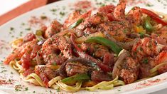 a white plate topped with pasta covered in meat and veggies