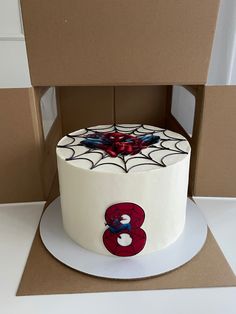 a white cake with red and blue decorations in a cardboard box on top of a table