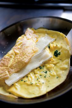 an omelet with cheese and parsley in a frying pan