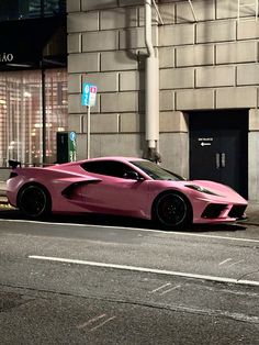 a pink sports car is parked on the side of the street in front of a building