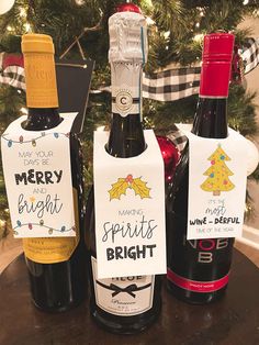 three bottles of wine sitting on top of a wooden table next to a christmas tree