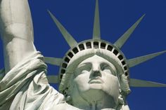 the statue of liberty has its head up and is looking upward into the blue sky