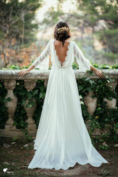 the back of a woman's wedding dress, with her arms on a wall