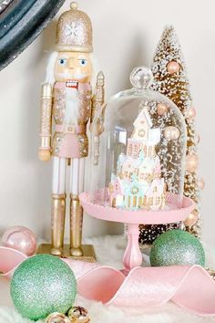 a nutcracker is under a glass clochel on a table with ornaments