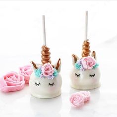 two unicorn cake pops with pink and blue flowers on them, sitting next to each other