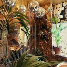 a mirror and plants in a room with gold tiles on the walls, along with mirrors hanging from the ceiling