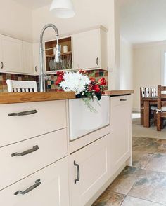 a kitchen with white cabinets and wooden counter tops, flowers in a vase on the dishwasher