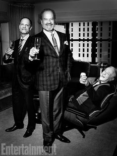 two men standing next to each other in a living room holding wine glasses and posing for the camera