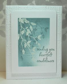 a white frame holding a card with leaves on it