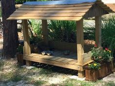 a wooden gazebo with a solar panel on top and potted plants around it