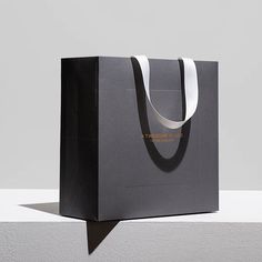 a black shopping bag sitting on top of a white table