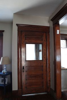 a wooden door in the corner of a room next to a lamp on a table