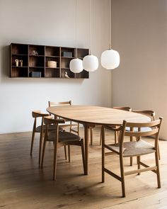 a dining room table and chairs in front of a book shelf with shelves on the wall