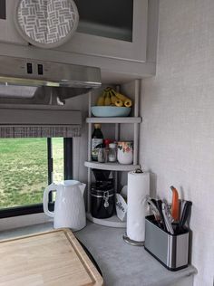 a kitchen area with a microwave, counter and shelves