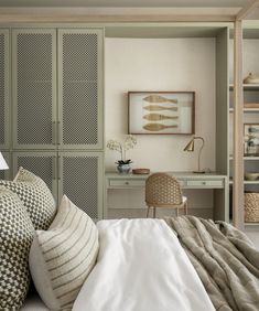 a bed with white sheets and pillows in a bedroom next to a bookcase filled with books