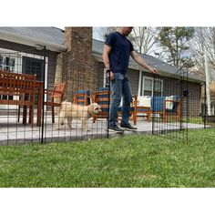 a man standing next to a dog in a fenced off area near a house