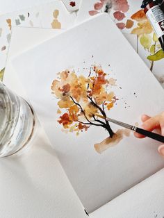 someone is painting a tree with watercolors on paper