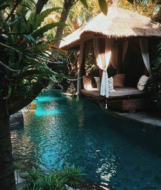 a gazebo sitting next to a swimming pool surrounded by palm trees and greenery