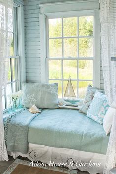 a bed sitting under a window next to a window sill with pillows on it