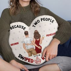 a woman holding a heart shaped pillow with two people on it