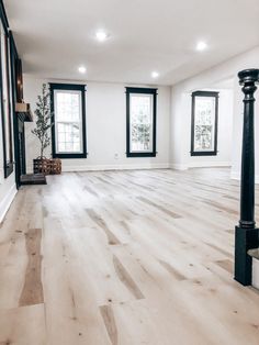 an empty living room with wood floors and black trim around the window sills