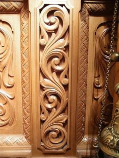 carved wood paneling on the side of a wall with chains hanging from it's sides