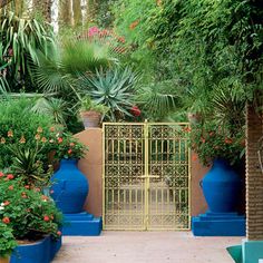 an outdoor garden with blue planters and yellow gate in the center, surrounded by greenery