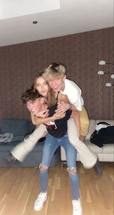 three young people are hugging in the middle of a room