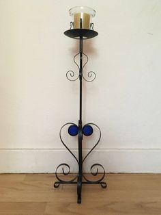 a metal candle holder with two blue glass balls on the bottom and a black stand