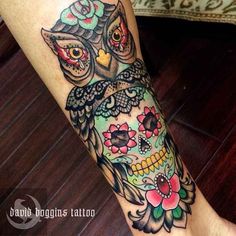 an owl tattoo on the leg of a woman's leg with flowers and leaves