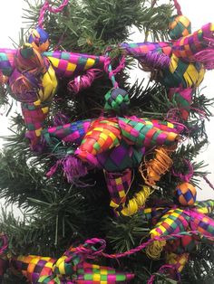 a christmas tree decorated with multi - colored ribbons and ornaments, hanging from it's branches