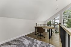 an empty room with a desk and chair on the other side of the room, looking out onto the woods