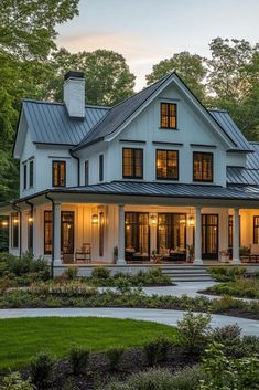 a large white house with lots of windows and lights on it's front porch