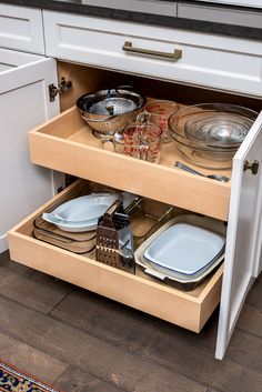 an open drawer in a kitchen filled with dishes