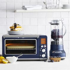 a blue toaster oven sitting on top of a counter next to plates and bowls